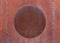 Fragment of old rusty unpainted metal surface with round plate in the middle. Textured background.