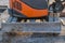 Fragment of orange cab of crawler excavator or bulldozer with a metal rectangular blade in front of it with the remains of soil