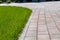 Fragment of pedestrian path and green lawn in park