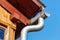 Fragment of the roof of a village house with drainpipe closeup against blue sky