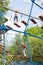Fragment of a rope park with an obstacle course with blurred images of climbing people in the background. Active entertainment and