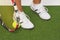 Fragment Shot of Legs of Caucasian Female Tennis Sportswoman Holding Racket with Ball Tightly Underneath, Standing On Artificial