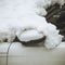 Fragment of a snow-covered white car with a folded rear-view mirror and drops on the glass