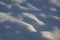 Fragment of a snowy hilly surface with small pits closeup