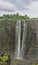 Fragment of Victoria Falls waterfall. Streams of water fall from the steep slopes of the gorge.