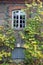 Fragment of the wall of an ancient stone house with a wooden window, dilapidated from time to time. Brickwork.