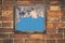 Fragment of the wall of an old house with a bricklaying of red brick and and view from small window with cloud sky