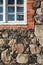 Fragment of weathered stone wall of medieval church with part of window built in later