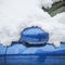 A fragment of a wet blue car covered with snow with a folded rear-view mirror. Closeup photo