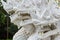 Fragment of white ceramic naga snake statue on stair of temple