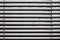 Fragment of the white Venetian blinds with lift cord and turning rod of a manual control on a foreground .