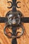 Fragment of a wooden fortified metal strips door with a metal handmade handle in the shape of a lion`s head