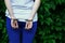 Fragment of a young criminal girl`s body with hands in handcuffs against a green blossoming ivy leaves background