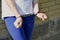 Fragment of a young criminal girl`s body with hands in handcuffs against a yellow brick wall background