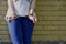 Fragment of a young criminal girl`s body with hands in handcuffs against a yellow brick wall background