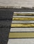 A fragment of a Zebra crossing, white and yellow stripes, across an asphalt road