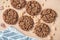 Fragrant chocolate granola cookies spread out on a beige cardboard background with brown sugar crystals and a gray napkin