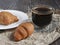 Fragrant croissants on a white plate and hot coffee. The concept of a quick breakfast at the workplace or breakfast with you