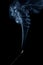Fragrant curls of blue smoke picturesquely rise above a smoldering incense stick on a black background. Fragrant Sandalwood for
