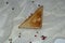 Fragrant freshly baked bread in the shape of a triangle. A slice on a white napkin with scattered peppercorns.