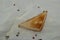 Fragrant freshly baked bread in the shape of a triangle. A slice on a white napkin with scattered peppercorns.