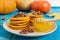 Fragrant golden pumpkin pancakes with honey and walnuts on a blue wooden background.