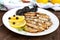 Fragrant Golden smoked small fish capelin `Sprat` on a white plate on a dark wooden background.