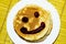 Fragrant pancakes that have just been cooked for a delicious breakfast, on pancakes is painted a face with delicious blueberry jam