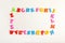 Frame of colorful magnetic letters on white background, flat lay with space for text. Alphabetic order