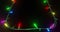 Frame of coloured christmas string lights flashing on black background, copy space