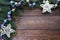 Frame of fir branches, violet, gold and turquoise Christmas tree balls and white stars on wooden brown background.