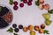 Frame of fruits and berries with copy space on a white wooden background. Harvest in summer and autumn