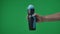 In frame on green background, chromakey male hand that holds, holds out a plastic black and blue sports bottle. Depicts