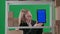 In a frame on a green background of chromakey. There is a young woman in a suit. The manager is shown in a warehouse