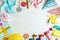 Frame made of different birthday party items on white wooden table, flat lay. Space for