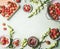 Frame made with fresh strawberries in colander and bowls with jam jar and spoon on kitchen table background with garden flowers