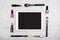 Frame made of makeup brushes, lipsticks and nail polish with tablet computer with blank screen on white marble