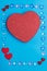 In a frame made of pebbles of hearts on a blue background, a box in the shape of a heart.