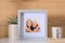 Frame with photo of elderly woman and her granddaughter on white table indoors