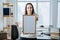 Frame picture, poster, diploma, certificate mockup in female hands. Young brunette woman holding empty blank wooden