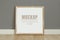 Frame, poster mock up with wooden frame. Empty frame standing on the wooden floor, grey wall. Free space for your