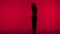 In the frame on a red background in the silhouette. Dances slender, beautiful girl. Demonstrates dance moves in the