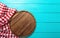 Frame of round cutting board and red plaid tablecloth. Blue wooden background in the cafe. Top view