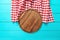 Frame of round cutting board and red plaid tablecloth. Blue wooden background in the cafe. Top view