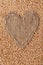 Frame in the shape of heart made of burlap with wheat