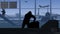 The frame shows an airport with a waiting room. A man is waiting for his luggage while it is checked by X ray scanners