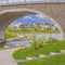 Frame Square Arched bridge over a glistening lake with a view of homes and snowy mountain