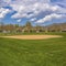 Frame Square Baseball or softball field with buildings and trees beyond the grassy terrain