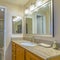 Frame Square Vanity unit with brown wooden cabinets and bright lights inside a bathroom