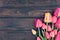 Frame of tulips on dark rustic wooden background. Spring flowers
